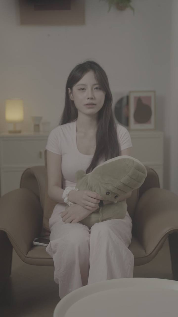 原始实拍 · 同一扶手椅场景的另一段口播，人物手势与玩偶位置发生变化。